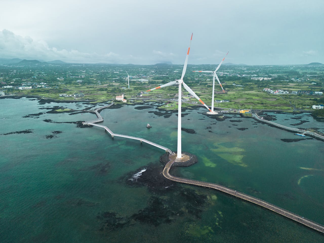 Scenic aerial shot of wind turbines along Jeju's coast, showcasing renewable energy.