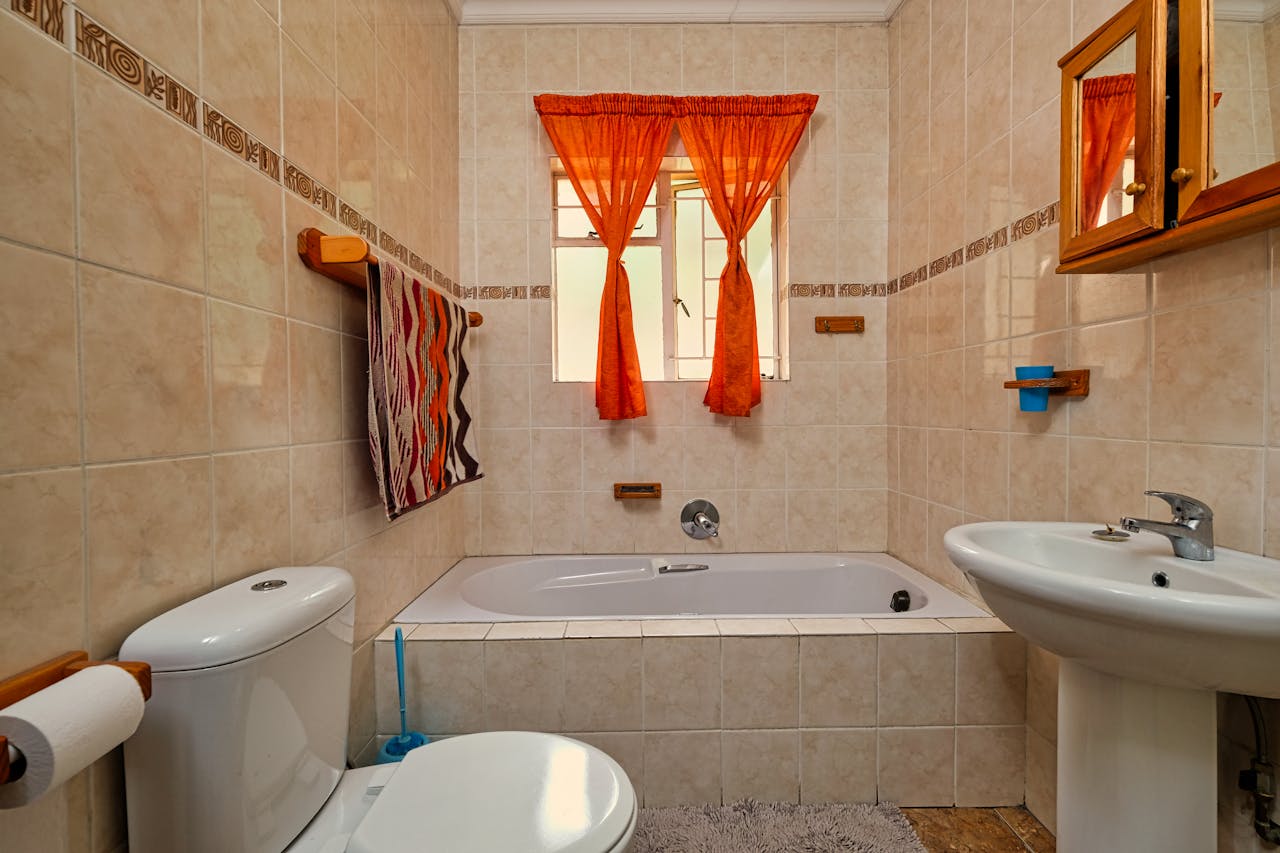 about-us A warm and inviting bathroom featuring modern fixtures and orange curtains.
